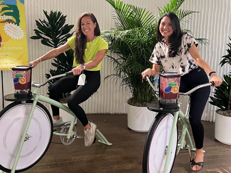 Dos personas pedaleando en bicicletas con batidora para preparar zumos
